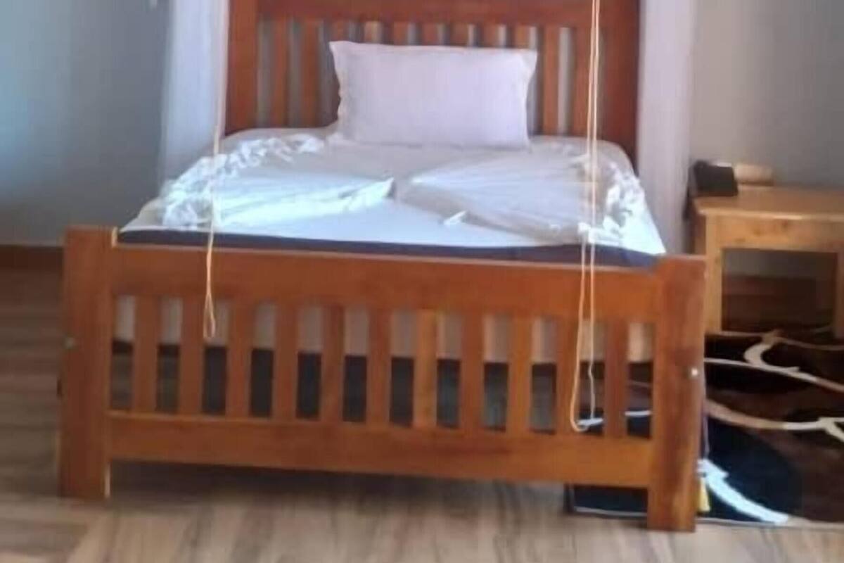 A wooden bed with a canopy, a wooden ceiling, and a small bedside table.