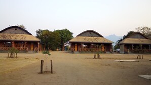 A row of rustic, single-story buildings with wooden railings and a dirt ground. - LAKE NYASA RESORT & CAMPSITE  (Matema)