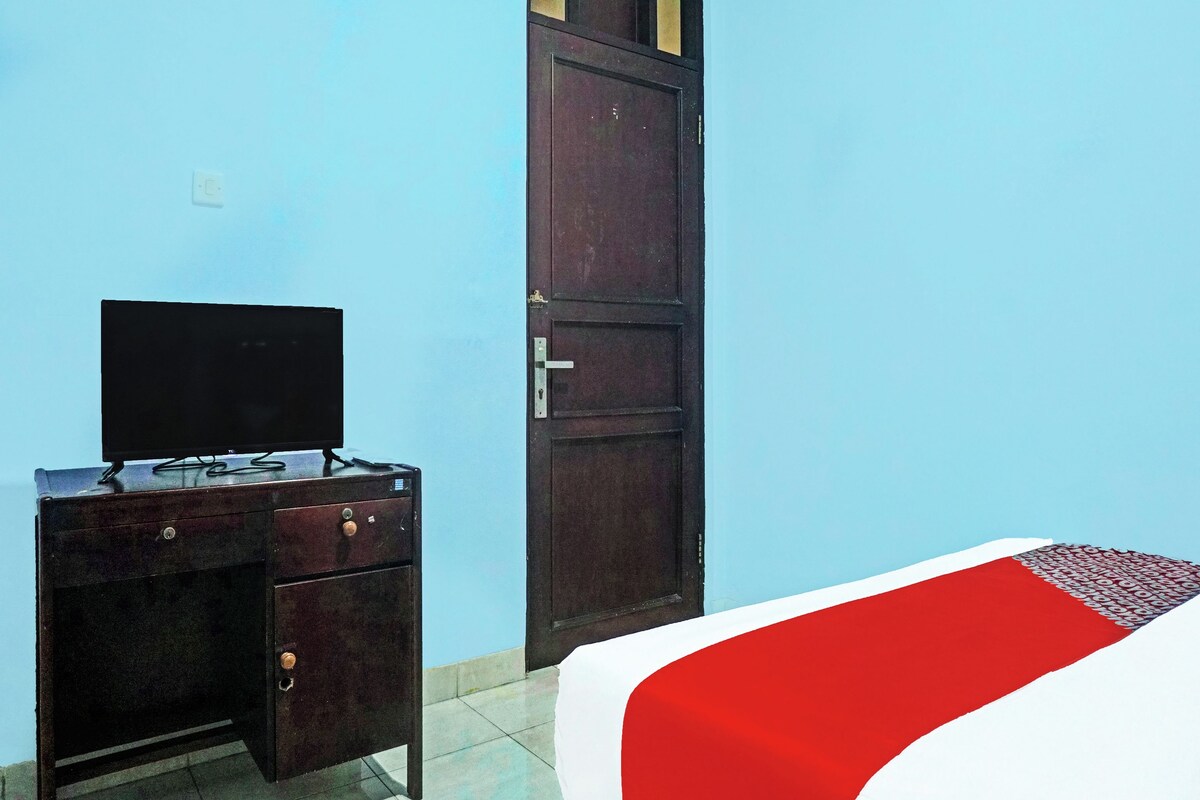 Una habitación con una cama, un televisor sobre un mueble de madera y una puerta.