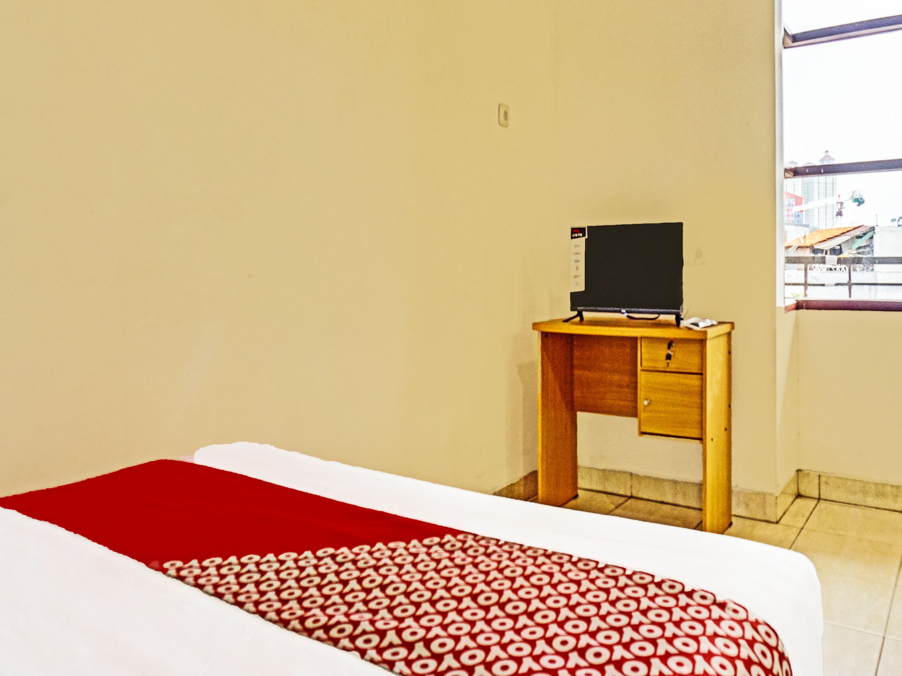 A hotel room with a bed, a desk, and a window.