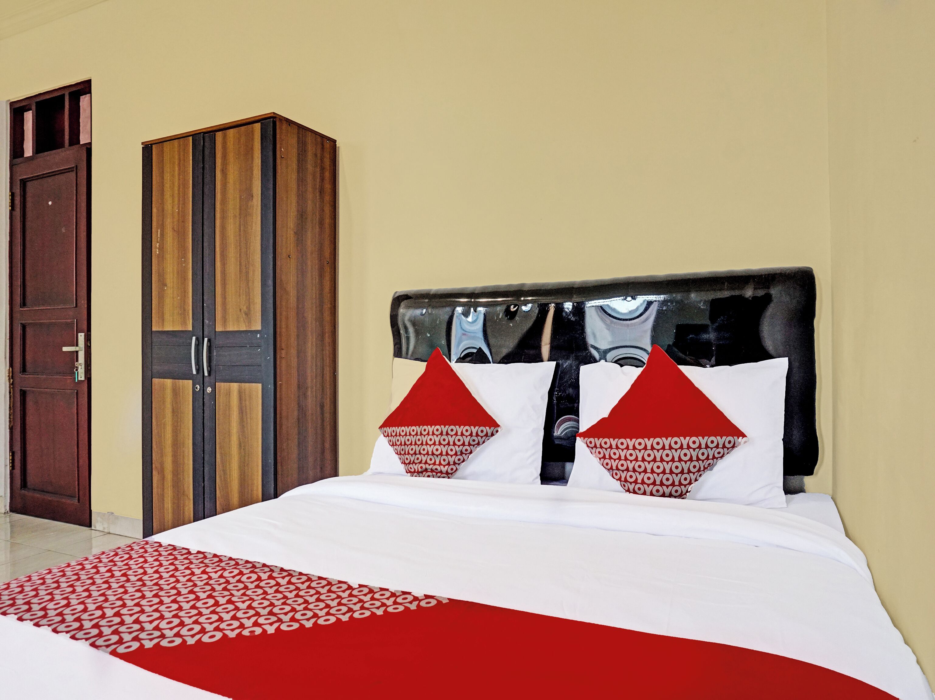A hotel room with a bed, a wardrobe, and a door.
