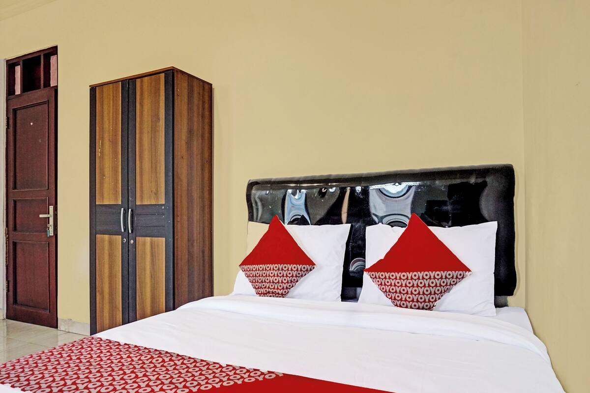 A hotel room with a bed, a wardrobe, and a door.