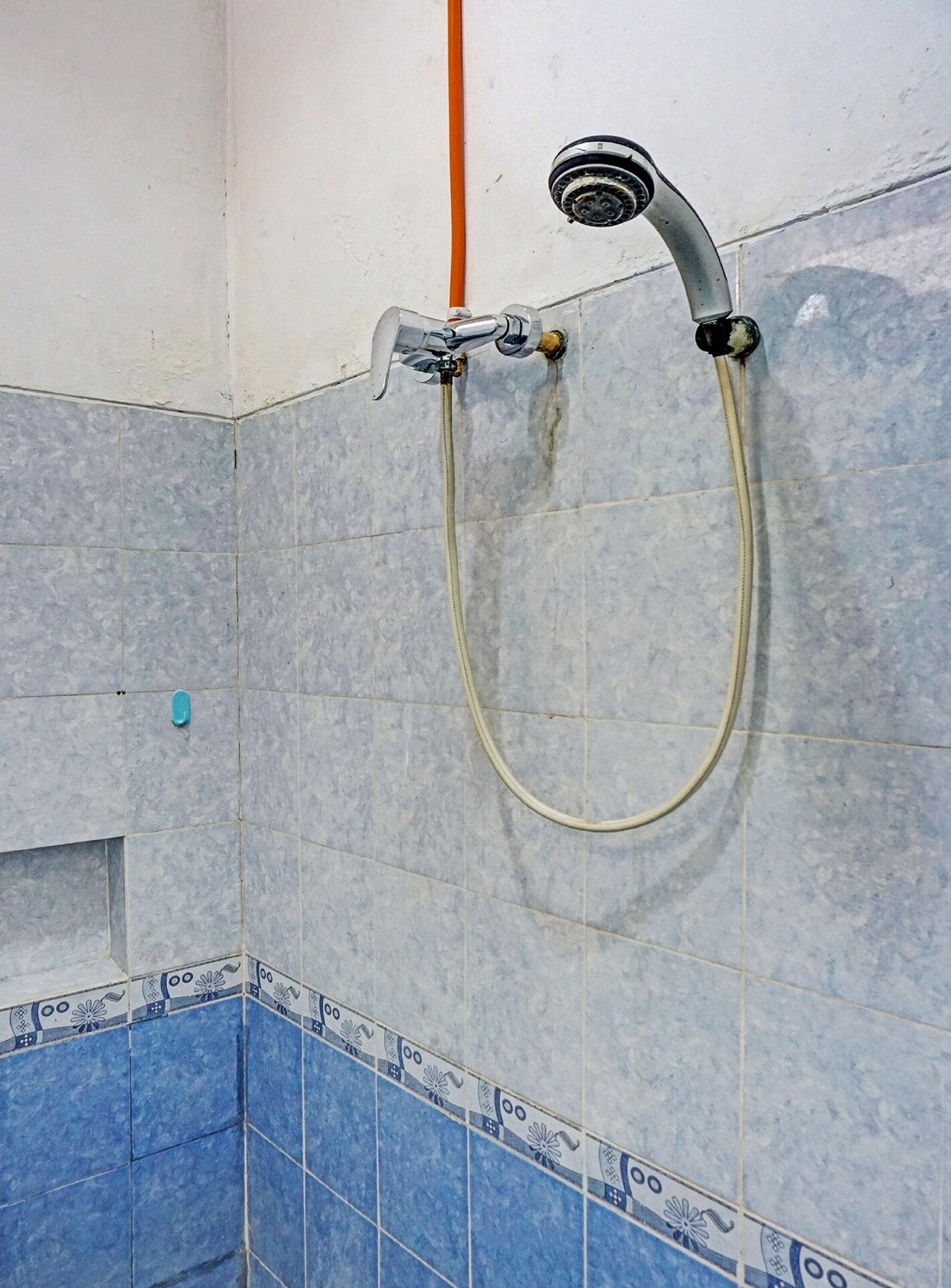 Ducha con rociador, paredes de azulejos y un diseño de esquina en azulejos.