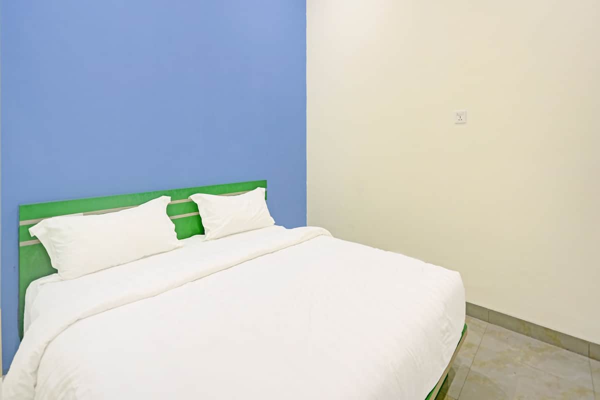 Ein Einzelbett mit weißer Bettwäsche in einem Zimmer mit blauen und weißen Wänden.