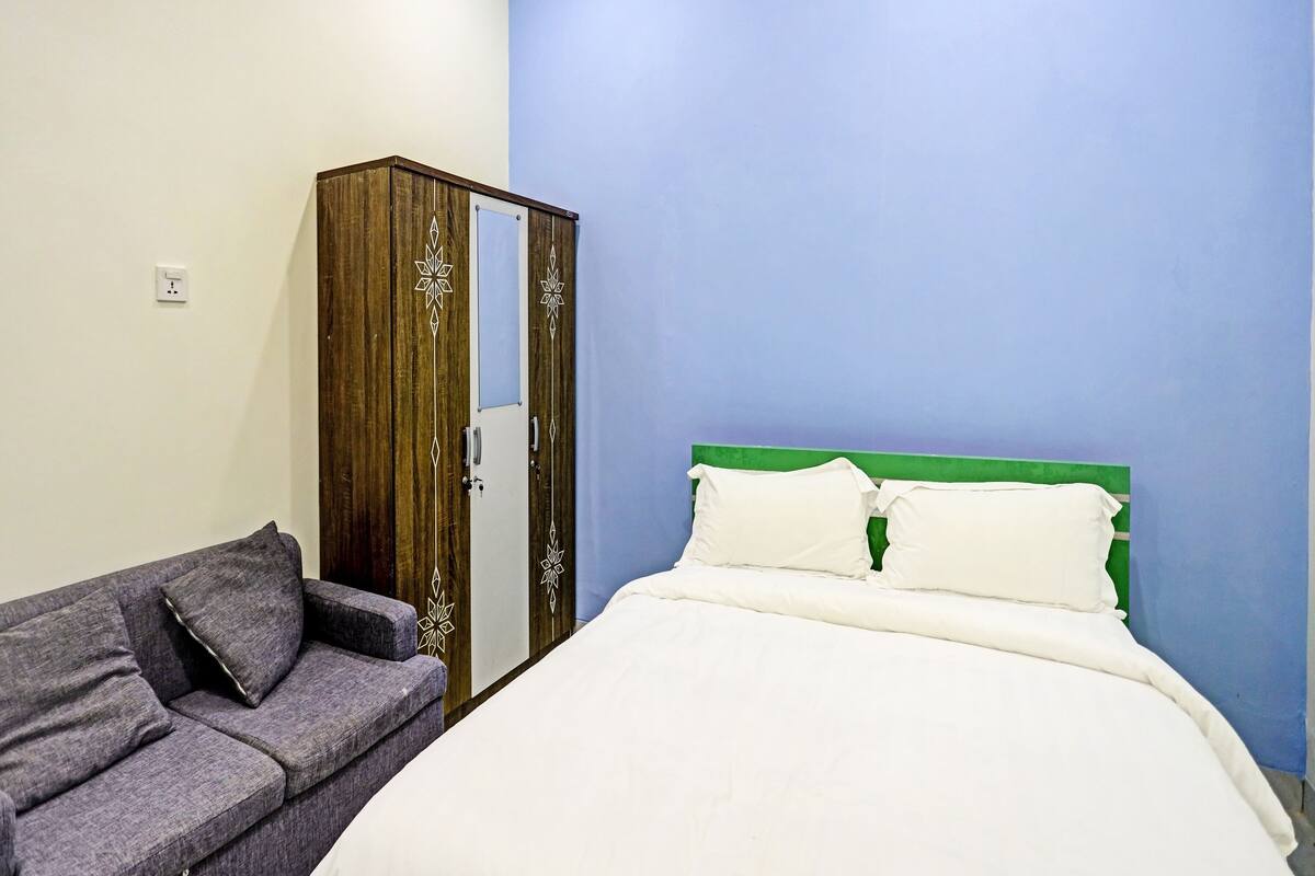 Ein Schlafzimmer mit einem Bett, einem grauen Sofa und einem Kleiderschrank.