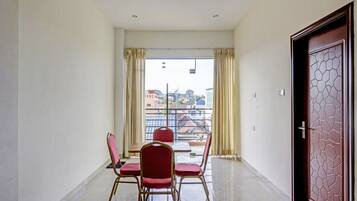 A balcony with a table and chairs, a view of buildings, and a door with a geometric pattern.