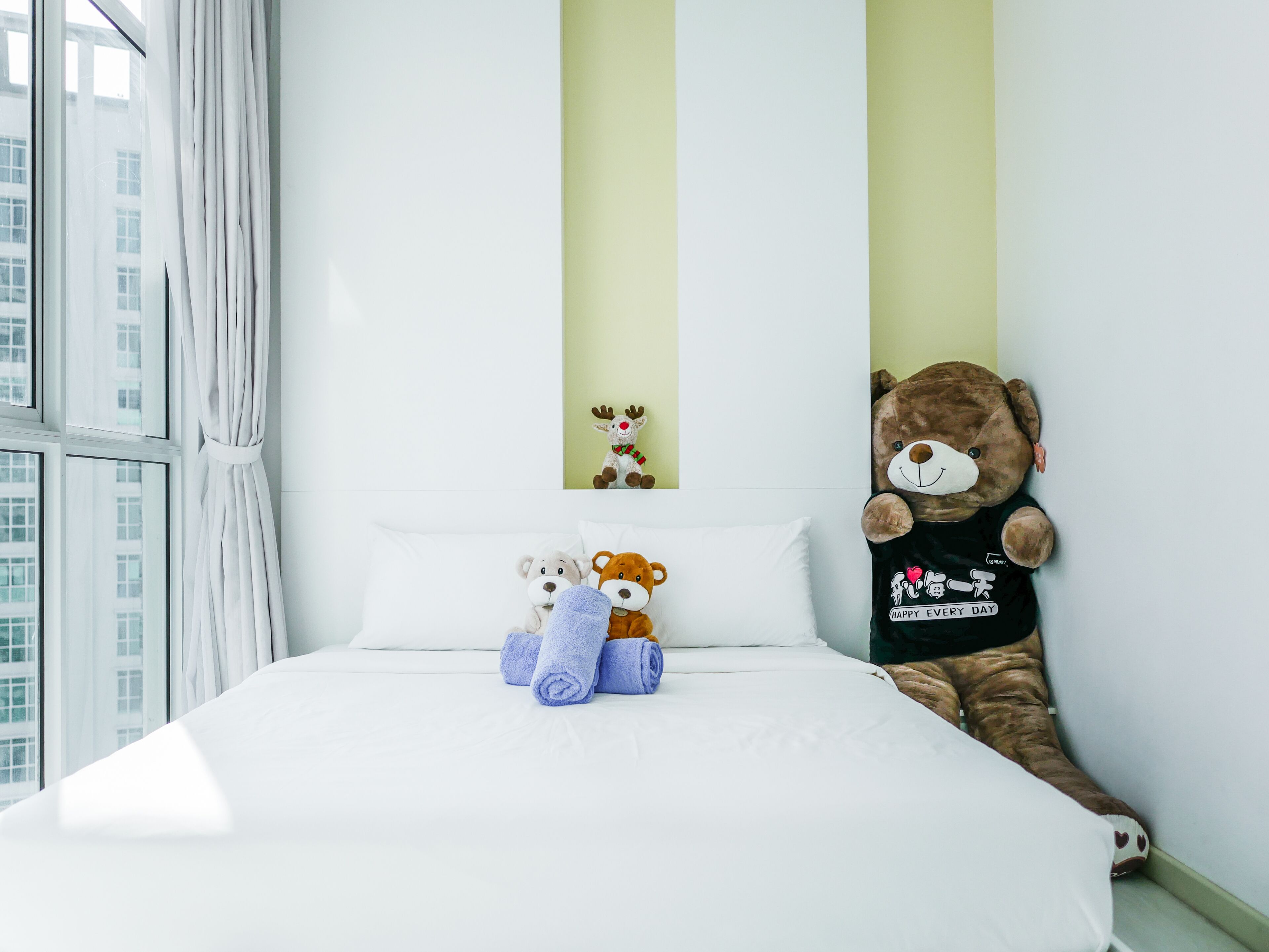 A bedroom with a bed, pillows, and a teddy bear.