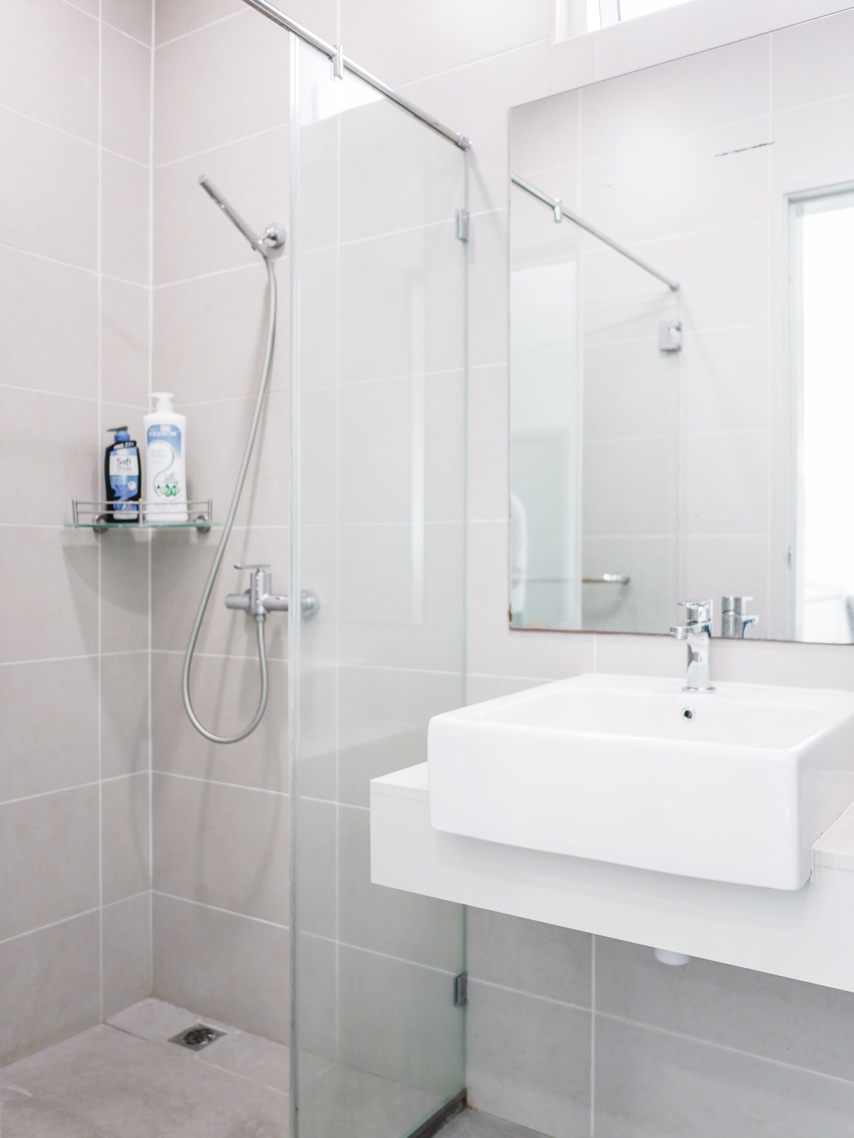 Un bany modern amb una cabina de dutxa de vidre, un lavabo blanc i un mirall damunt.
