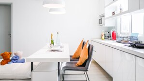 A modern kitchen with white cabinetry, a dining table with chairs, and a hanging pendant light.