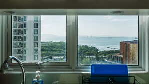 A bathroom with a window view of a bridge, buildings, and greenery.