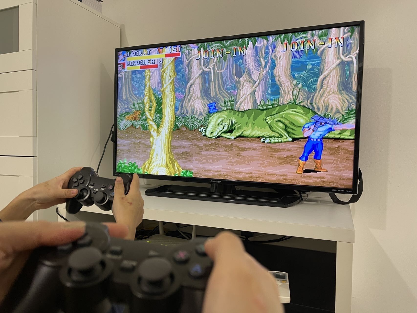 Ein Fernseher zeigt ein Videospiel, an dem zwei Spieler mit Spielcontrollern teilnehmen.