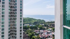 A high-rise building with multiple balconies, a view of a bridge, and a coastal area with various buildings.