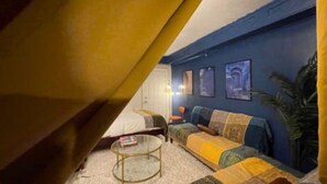 A cozy living room with a sofa, a coffee table, and a bookshelf. - Moroccan Lover's Oasis: 2BR/ 2BA Great for Large Groups and Families (Queens)