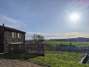 Un bâtiment en pierre avec une fenêtre, un champ herbeux et une clôture.