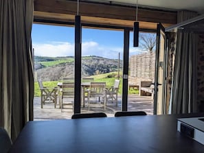 Une chambre avec vue sur une terrasse en bois et sur du mobilier d’extérieur.