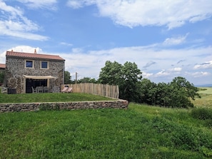 Une maison en pierre dotée d’un patio couvert et d’un mur en pierre.
