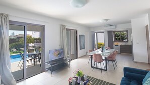 Una sala de estar moderna con televisor, comedor y cocina.