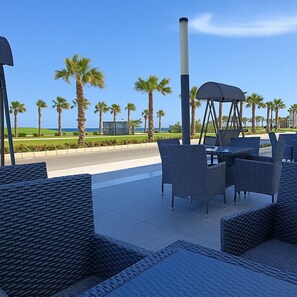 Relax in a seaside setting with comfortable wicker furniture and a scenic view.