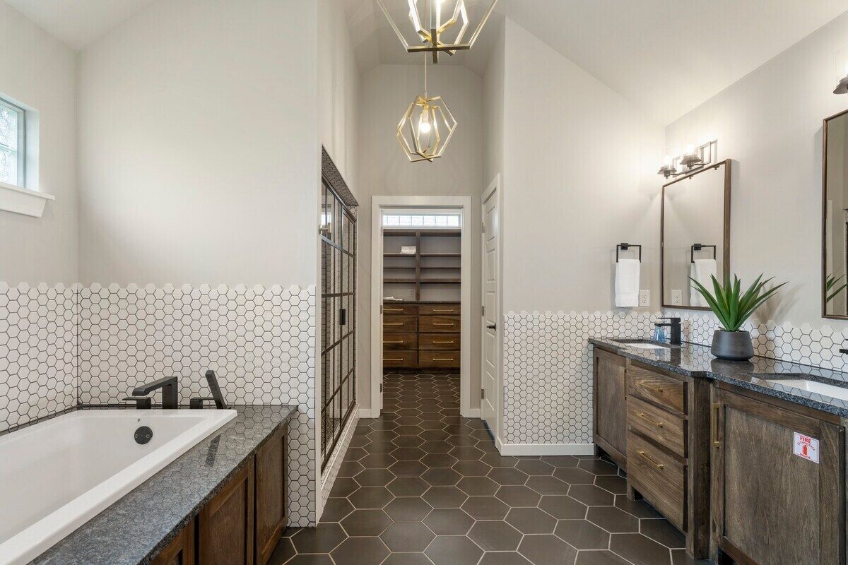 Une salle de bain moderne avec une grande baignoire, un meuble-lavabo avec un miroir et un sol carrelé de motifs hexagonaux.