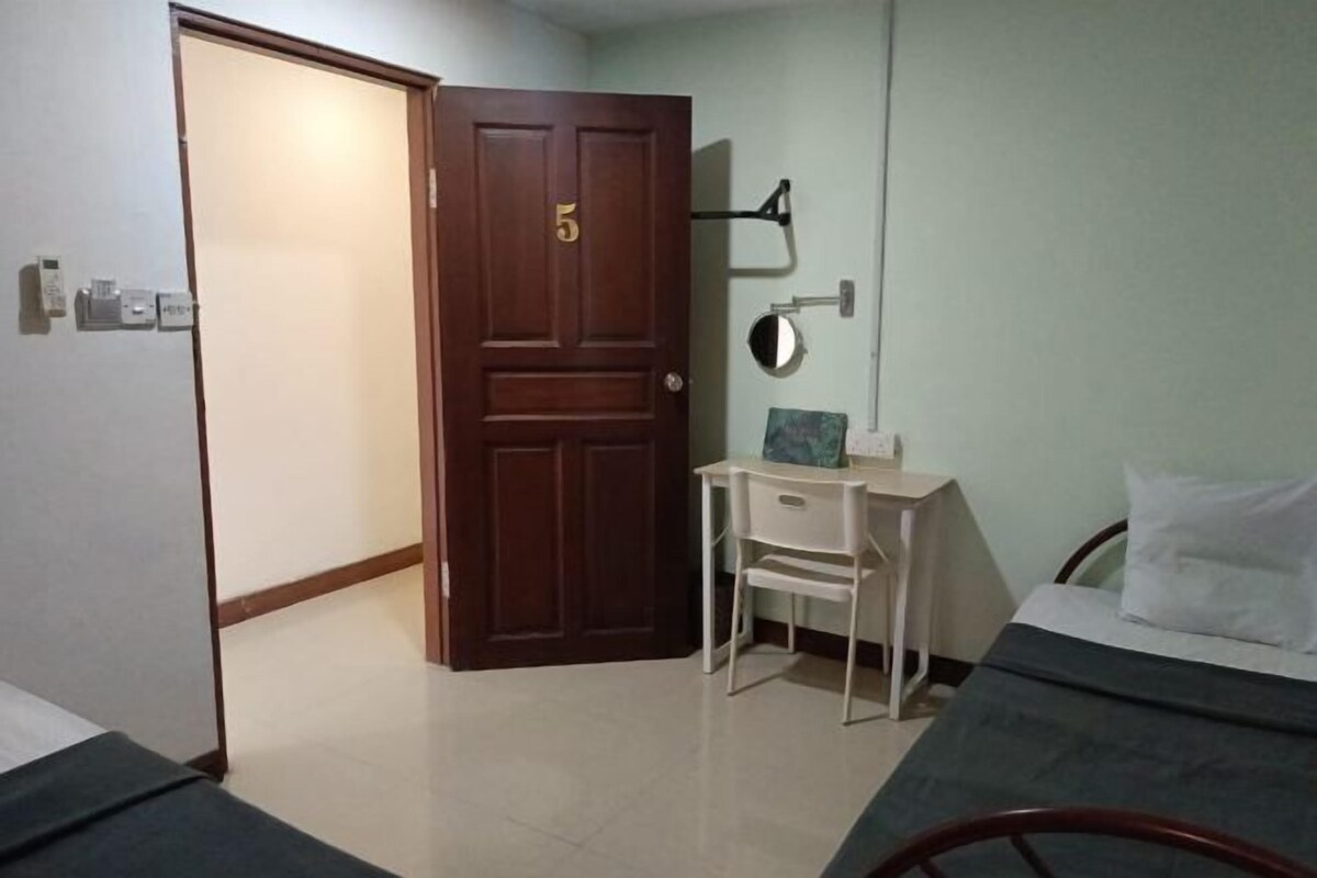 A room with a bed, a desk, a chair, and a door with a number.