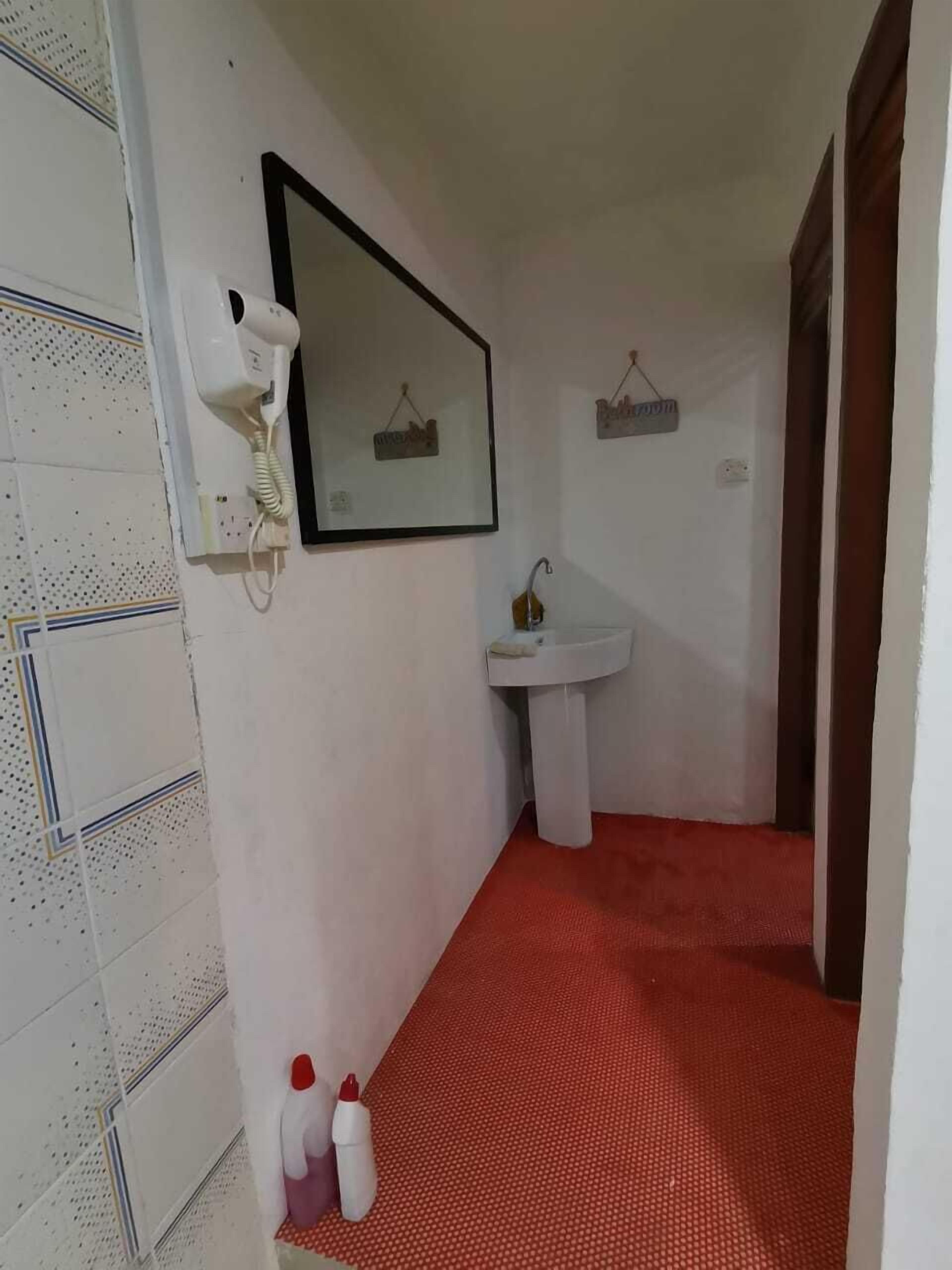 A narrow hallway with a red carpet, a white sink, and a telephone mounted on the wall.