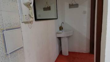 A narrow hallway with a red carpet, a white sink, and a telephone mounted on the wall.