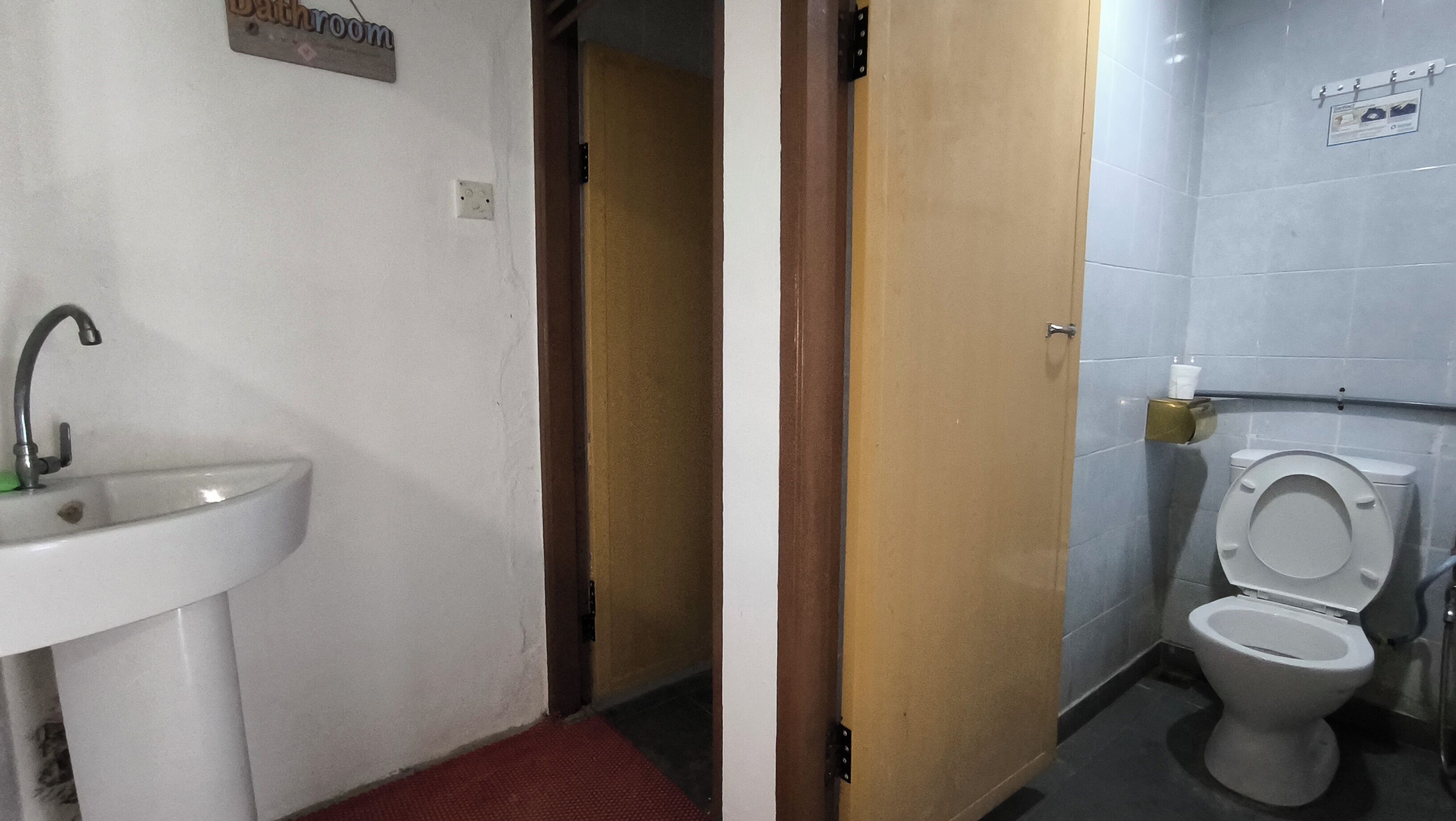 A bathroom with a sink, toilet, and a door leading to another room.
