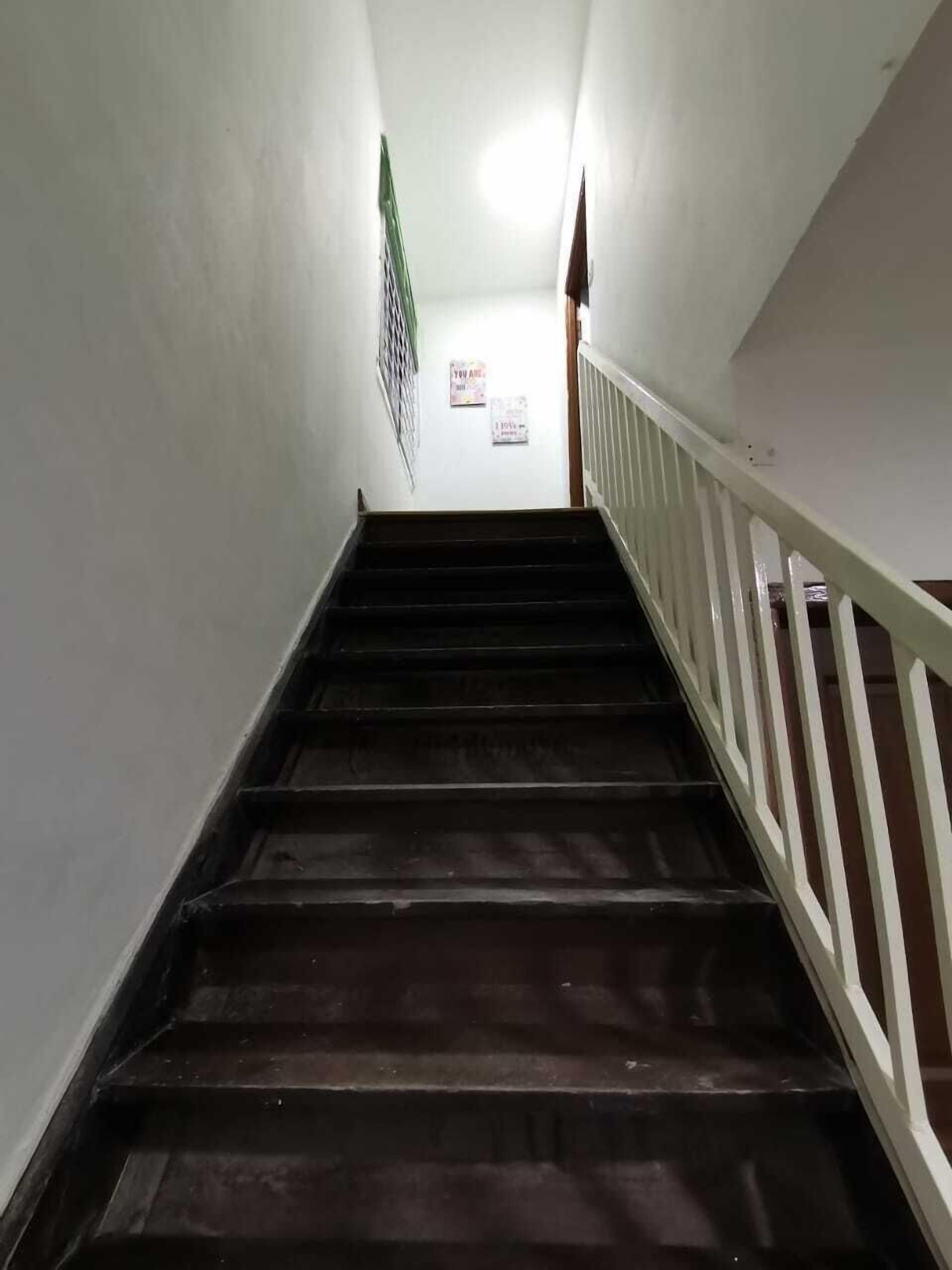 A staircase with wooden steps and white railings leading to an upper floor.