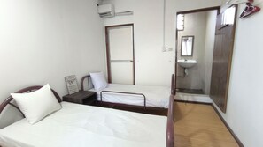 A small, simple room with a single bed, a bedside table, a mirror, and a small window. - Natol Homestay - Kenyalang Park  (Kuching)