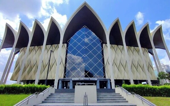 A modern building with a unique architectural design, featuring a central glass facade and multiple pointed structures around it. - Natol Homestay - Kenyalang Park  (Kuching)