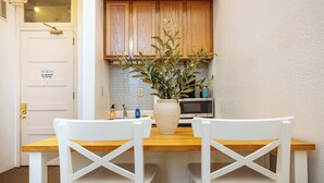 Una cocina pequeña con armarios blancos, un microondas y una planta en maceta sobre la encimera.