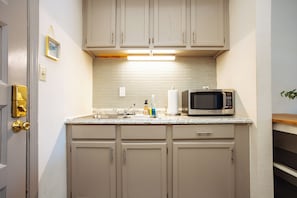 Una cucina con mobili beige, un forno a microonde, un lavello e un quadro appeso al muro.