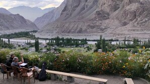 A rustic outdoor seating area with a view of a valley and mountains. - Hotel The Stone Palace (Leh)