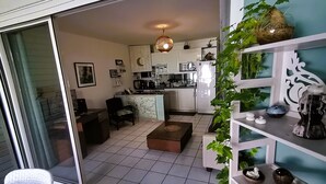 Une cuisine moderne avec des meubles blancs, un coin repas comprenant une table et des chaises, et une porte-fenêtre coulissante donnant sur un balcon.