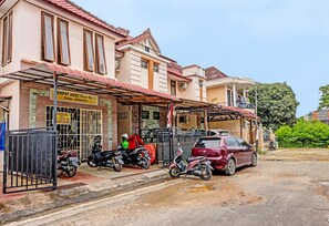 Un edificio con un cartel, un área techada y motocicletas y un coche estacionados.