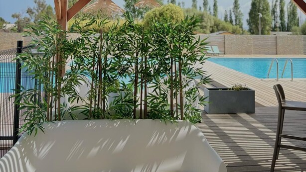 A wooden deck with hanging wicker lamps, a pool, and a white lounge chair. - les hameaux de saint cyprien (Lecci)