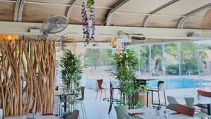 An indoor dining area with tables and chairs, a ceiling fan, hanging plants, and a view of the outdoors. - les hameaux de saint cyprien (Lecci)