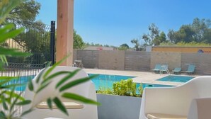 A covered outdoor area with a pool, white lounge chairs, and a wooden ceiling structure. - les hameaux de saint cyprien (Lecci)