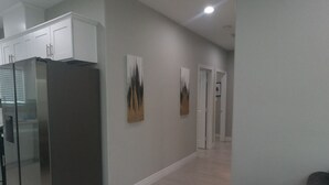 A modern kitchen with a stainless steel refrigerator, white cabinets, and a hallway leading to a door. - Unwind in insta-worthy Style: Dream Getaway Awaits! Private! Luxury Redefined! (San Bernardino)
