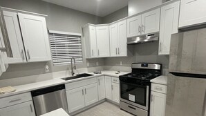 A modern kitchen with white cabinets, stainless steel appliances, and a marble countertop. - Unwind in insta-worthy Style: Dream Getaway Awaits! Private! Luxury Redefined! (San Bernardino)