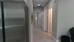 A hallway with a refrigerator, a trash bin, and a door leading to a room. - Unwind in insta-worthy Style: Dream Getaway Awaits! Private! Luxury Redefined! (San Bernardino)