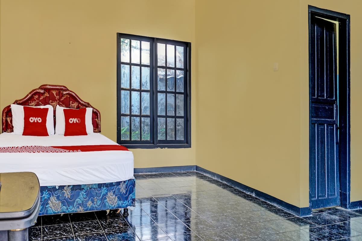 A hotel room with a bed, a window, a door, and a tiled floor.