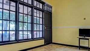 A room with large windows, a closed door, and a television on a stand. - SPOT ON 91798 Hotel Grand Mutiara (Cikampek)