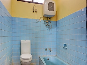 A bathroom with blue tiles, a white toilet, a bathtub, and a water heater mounted on the wall.