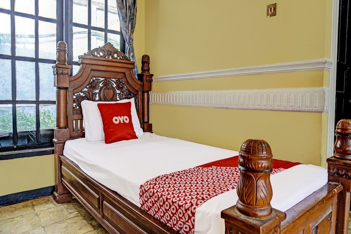 A bed with a wooden headboard, a red pillow with 'YOYO' text, and a patterned red blanket.