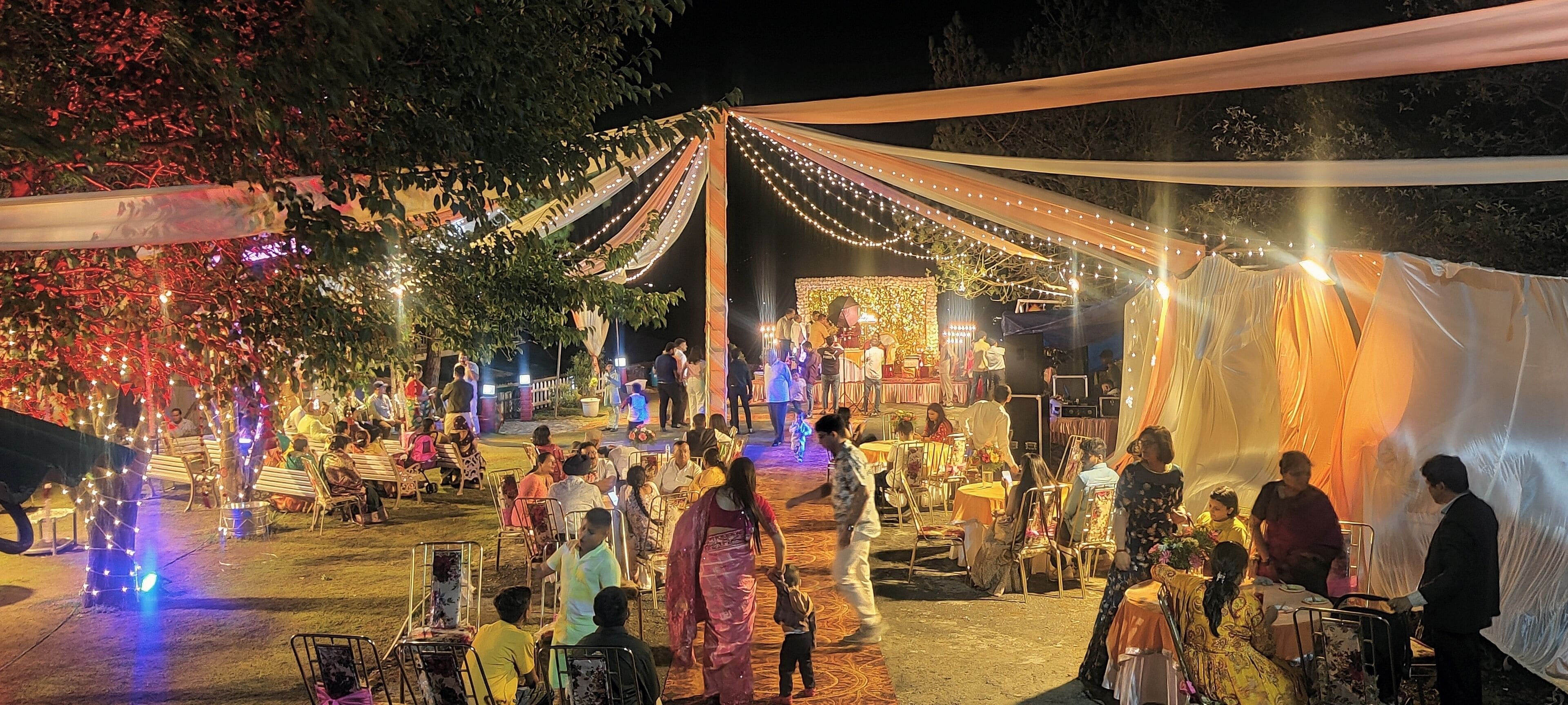 An outdoor event with a stage, seating, and string lights.