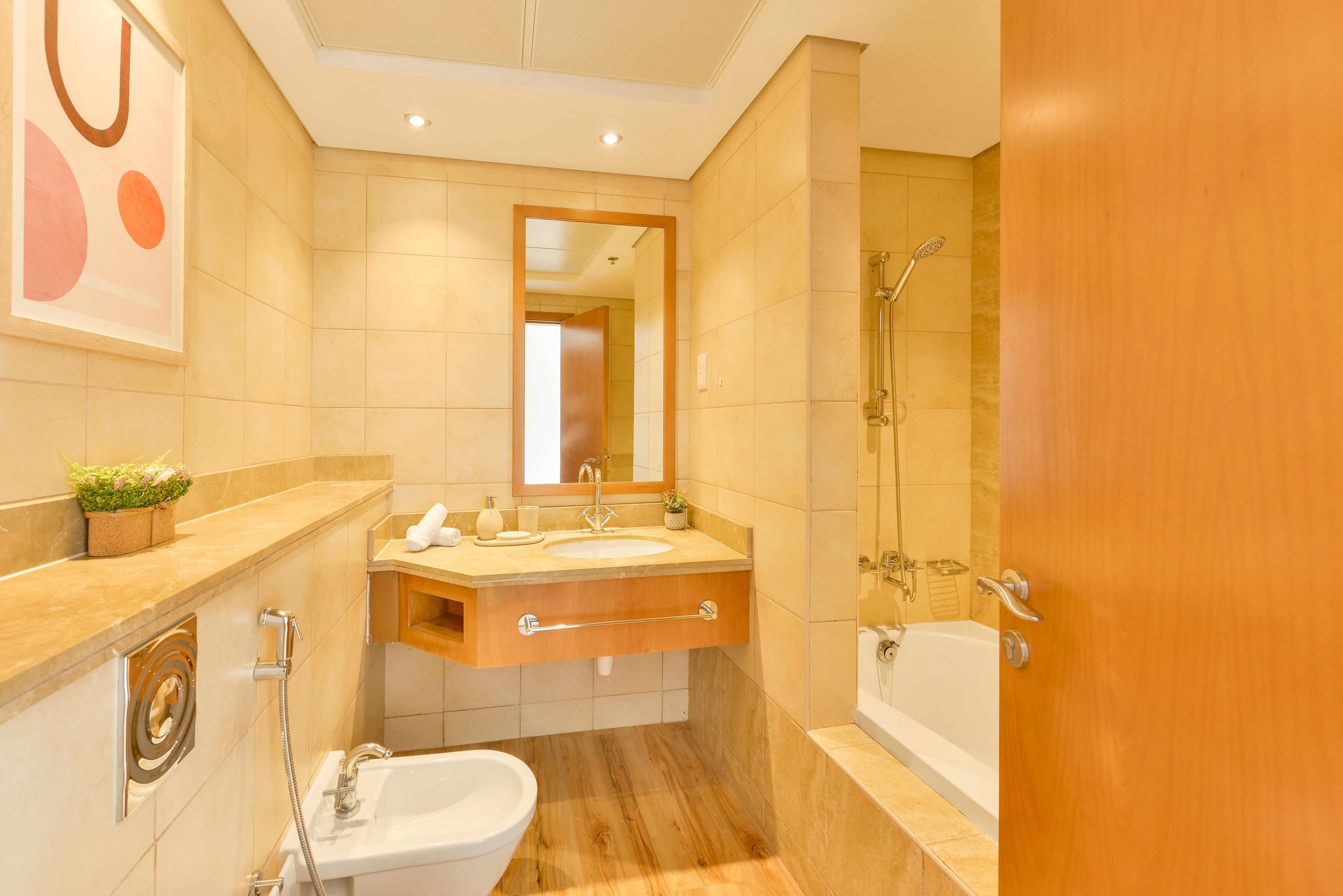 A modern bathroom with a sink, vanity, bidet, and bathtub.