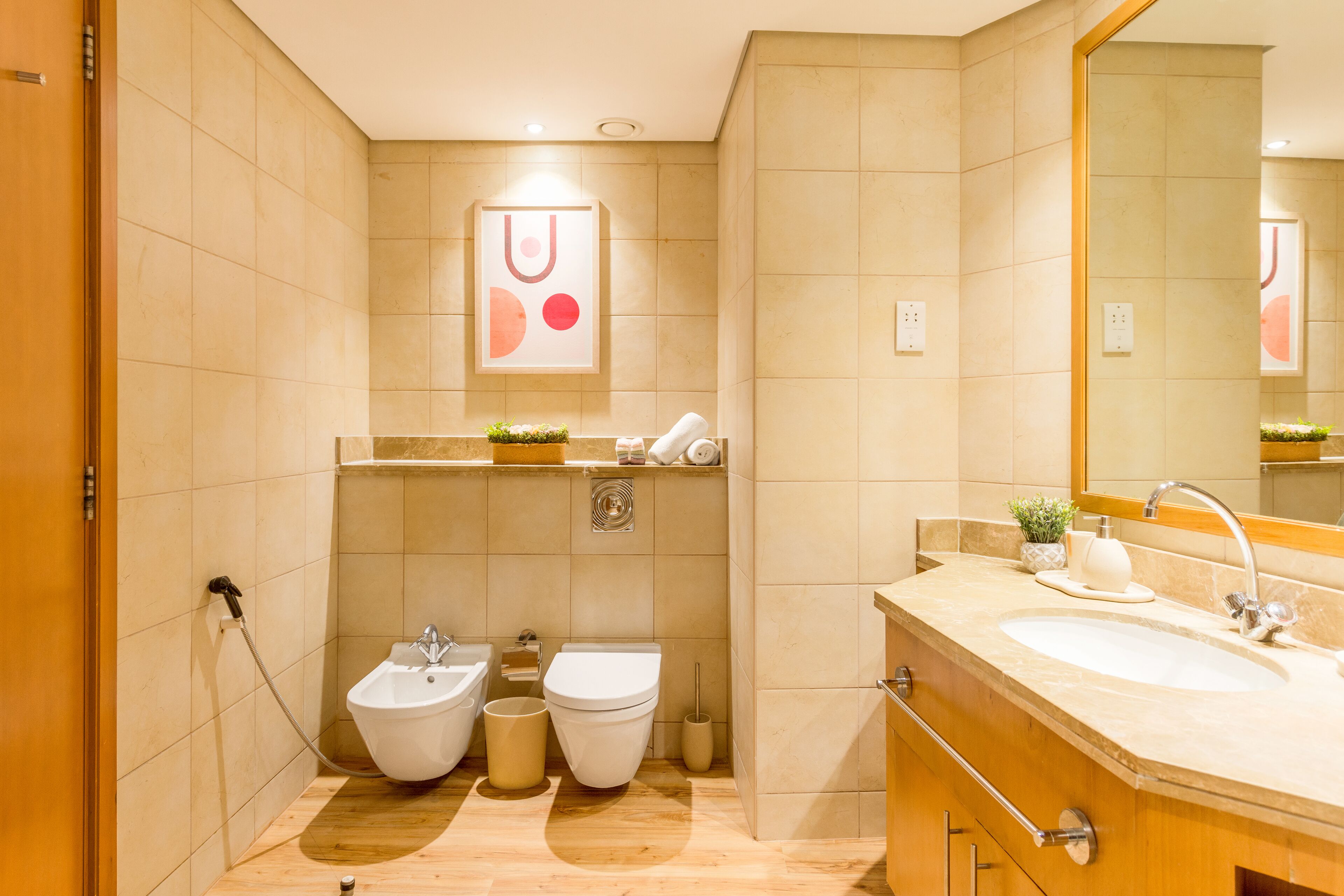 Une salle de bain moderne équipée de deux toilettes, d’un bidet, d’un lavabo et d’un miroir.