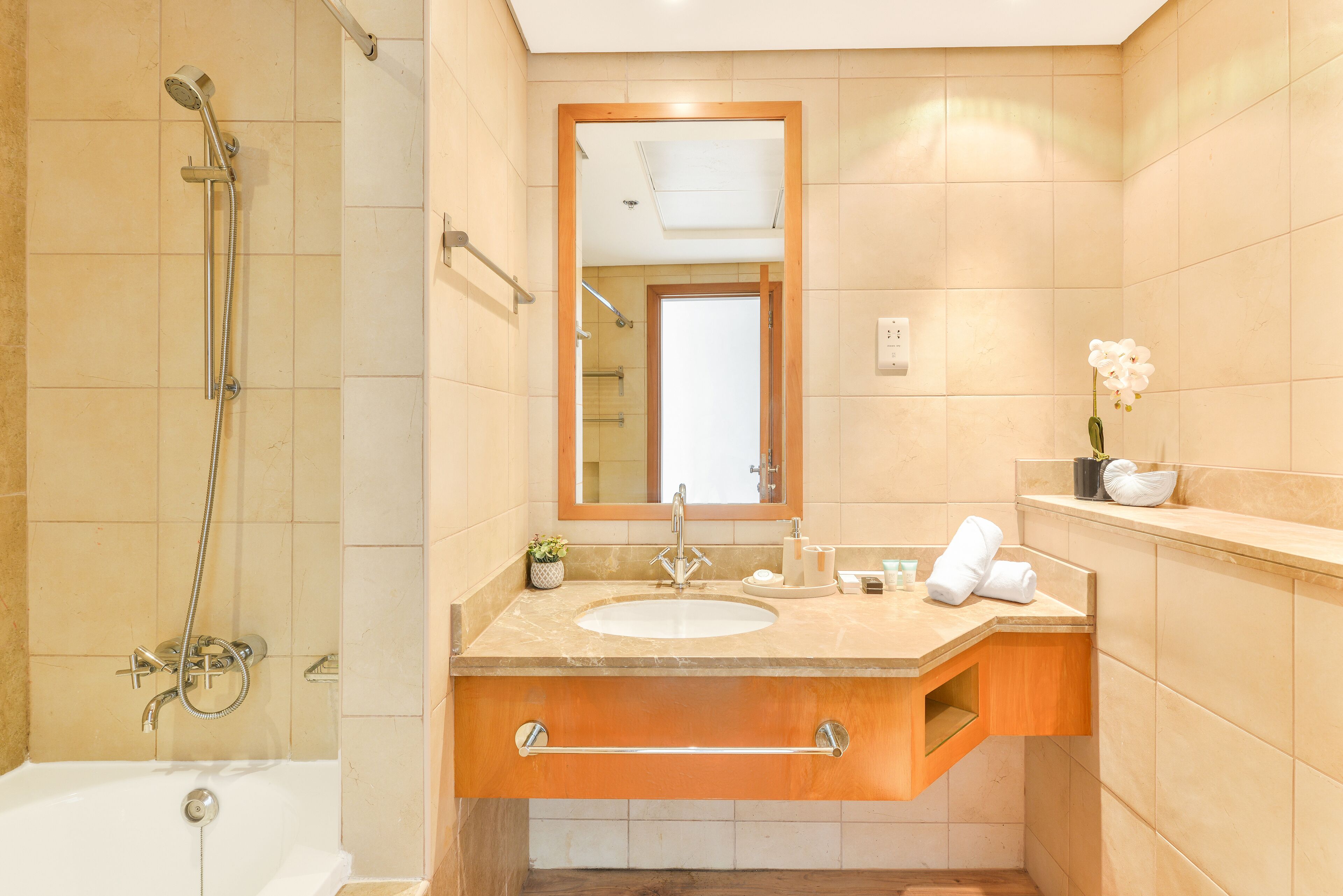 A bathroom with a bathtub, a shower, a sink with a mirror, and a towel rack.