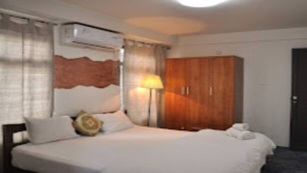 Una habitación de hotel con una cama, un armario y una lámpara.